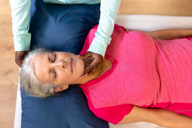 Female Physiotherapist Giving Neck Massage To Active Senior Woman In