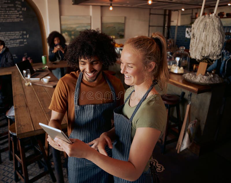 High angle view of young cafe owners standing using digital tablet wearing apron royalty free stock images