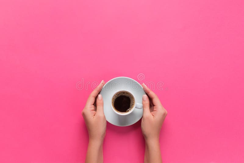 High angle of woman hands holding coffee cup on pink background Minimalistic style. Flat lay, top view isolated royalty free stock photos