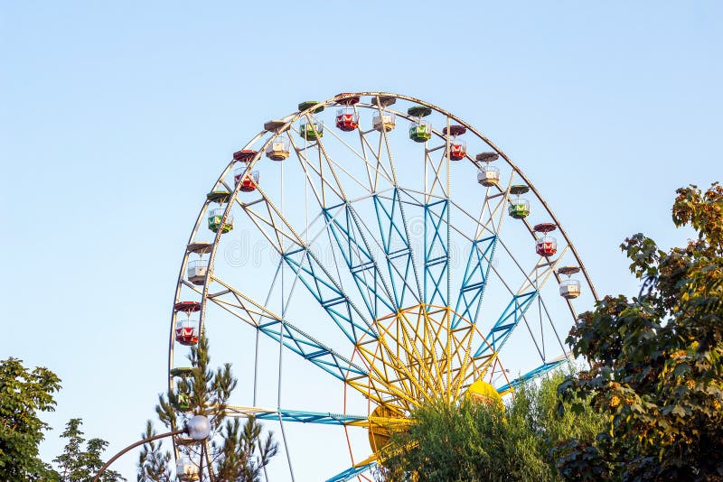 High carnival Ferris wheel in the amusement park in summer spinning against the blue sky. stock image High carnival Ferris wheel in the amusement park in summer spinning against the blue sky. stock image