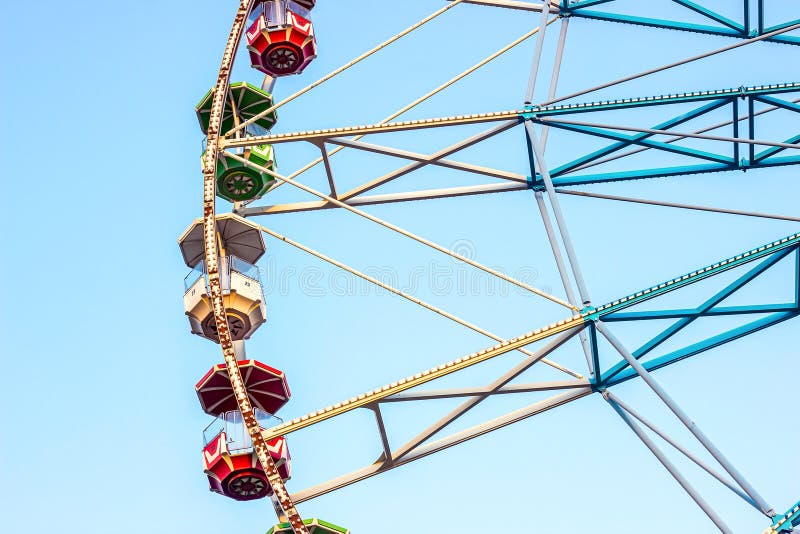 High carnival Ferris wheel in the amusement park in summer spinning against the blue sky. royalty free stock photo High carnival Ferris wheel in the amusement park in summer spinning against the blue sky. royalty free stock photo