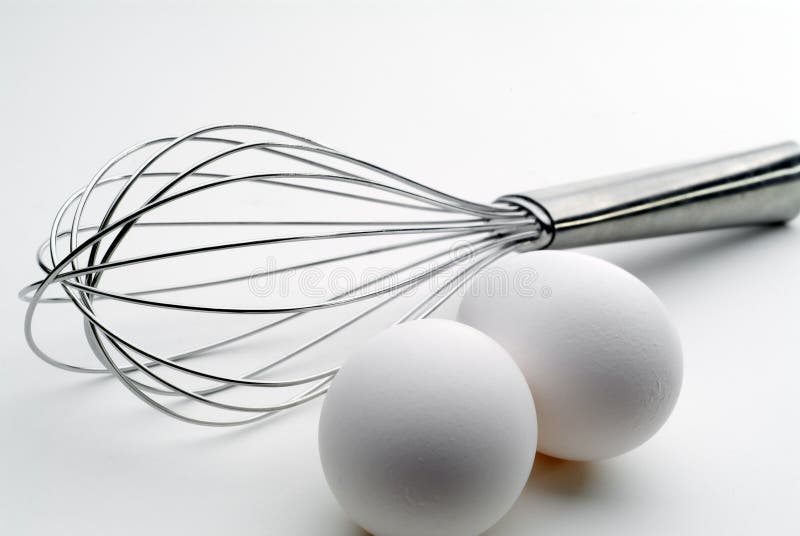High contrast tilted view of a whisk and 2 eggs royalty free stock photo