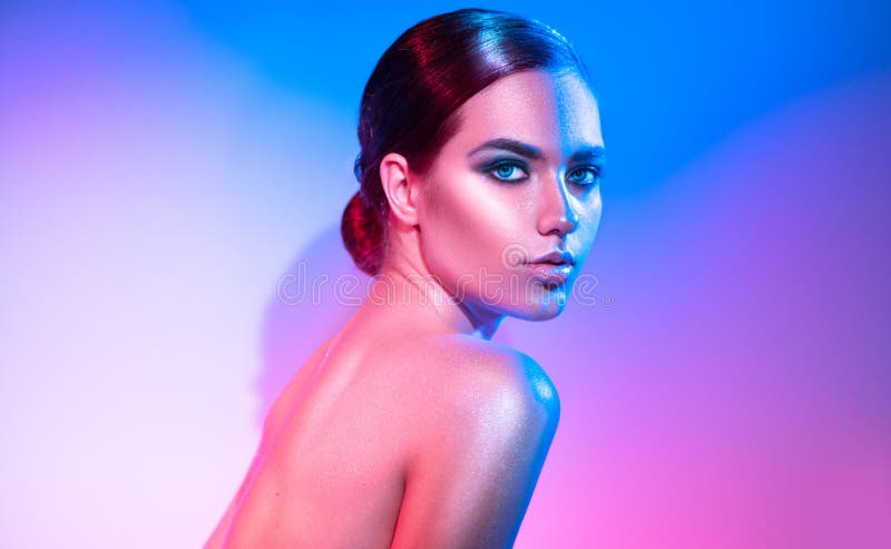 High fashion model girl in colorful bright sparkles and neon lights posing in studio. Portrait of beautiful woman