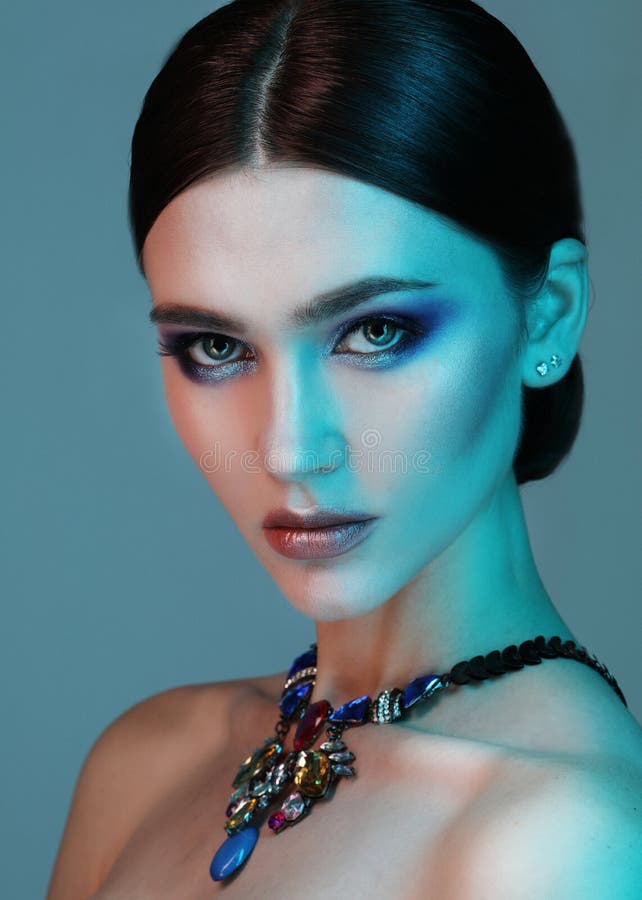 High Fashion model woman posing in studio. Portrait of beautiful sexy girl wearing jewelry with trendy make-up