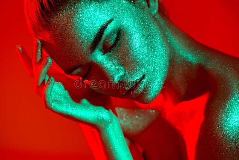 High Fashion model woman in colorful bright sparkles and neon lights posing in studio, portrait of beautiful sexy girl