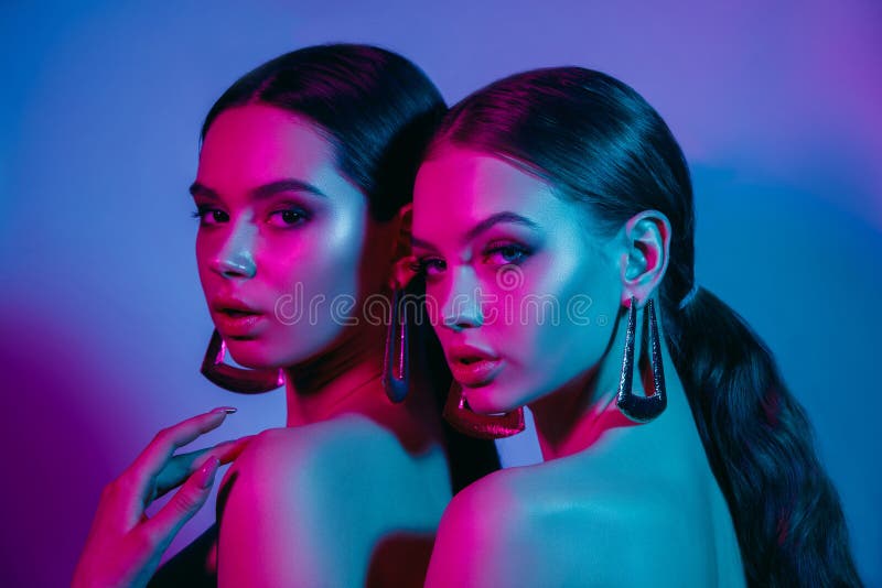 High Fashion models in colorful bright neon lights posing at studio