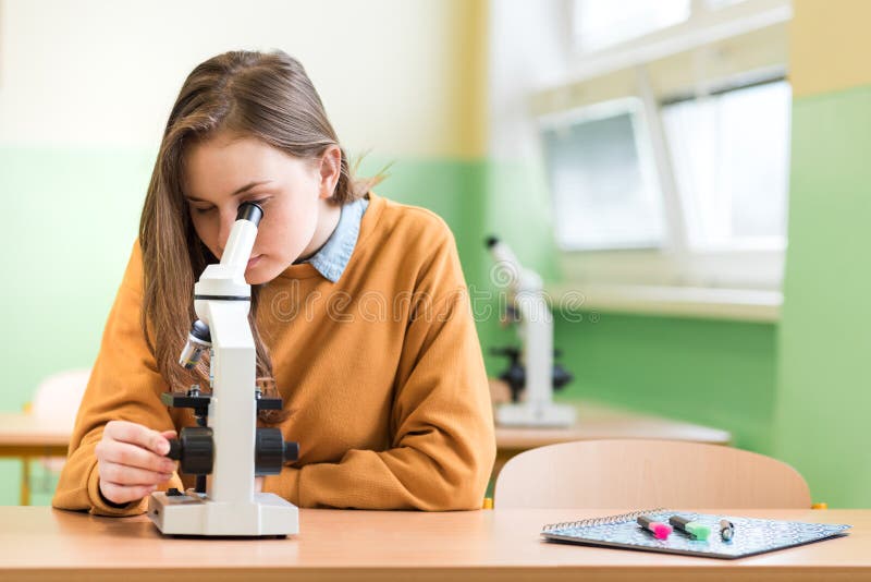 Student pomocí mikroskopu zkoumat vzorky v hodině biologie.