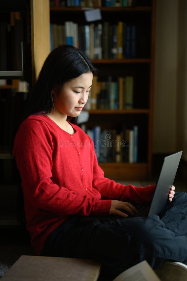 High school student girl using laptop and siting on library floor stock photos
