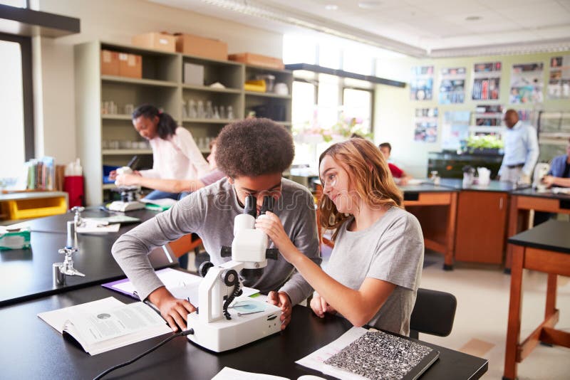 High School Students Looking Through Microscope In Biology Class royalty free stock photography