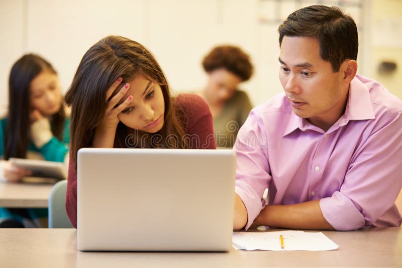 High School Teacher Helping Stressed Pupil In Class stock photo High School Teacher Helping Stressed Pupil In Class stock photo