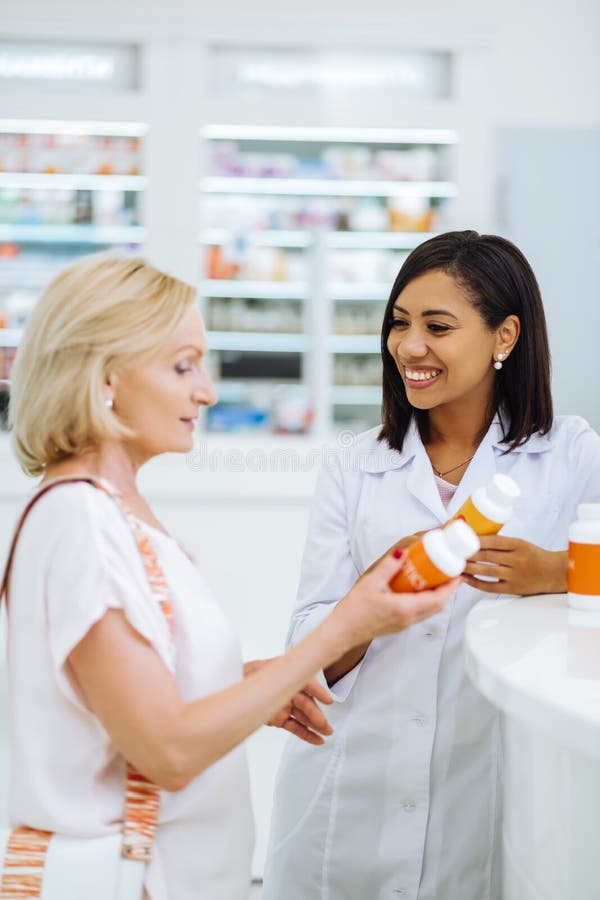 Cheerful dark-skinned chemist consulting her mature client stock photos Cheerful dark-skinned chemist consulting her mature client stock photos