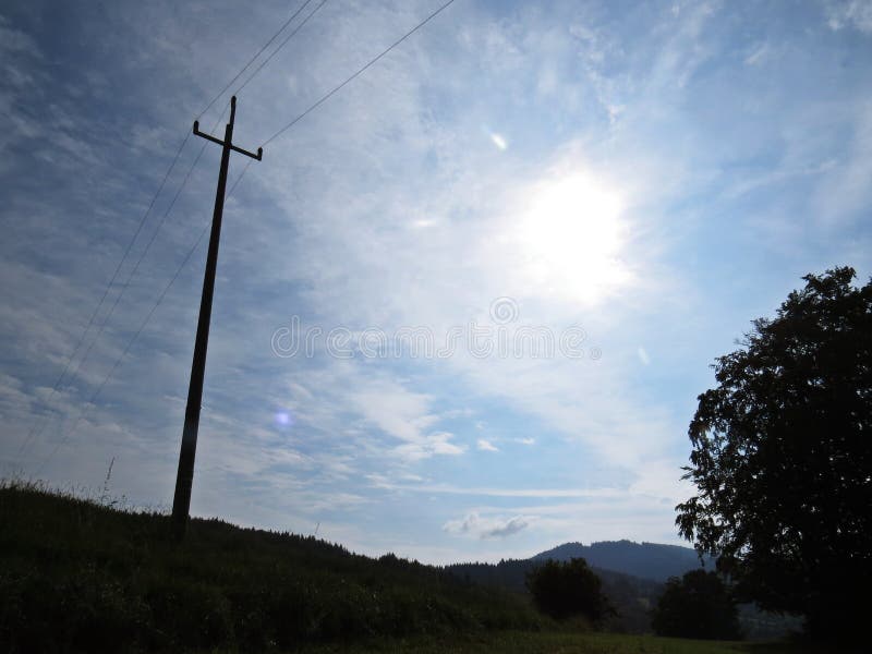 High Voltage Electricity Column Silhouette Cross with Background of Blue Sky, Sun and White Clouds royalty free stock photography High Voltage Electricity Column Silhouette Cross with Background of Blue Sky, Sun and White Clouds royalty free stock photography