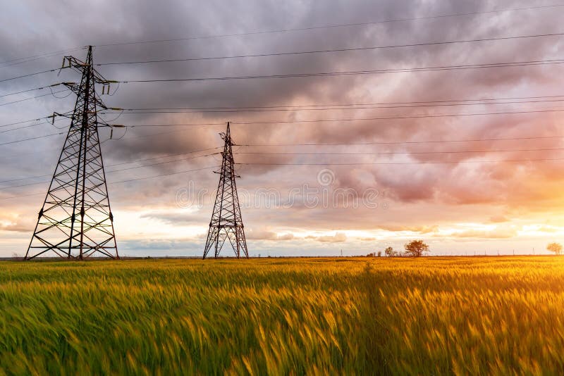 High-voltage power lines passing through a green field, on the background of a beautiful cloudy sky royalty free stock photography High-voltage power lines passing through a green field, on the background of a beautiful cloudy sky royalty free stock photography