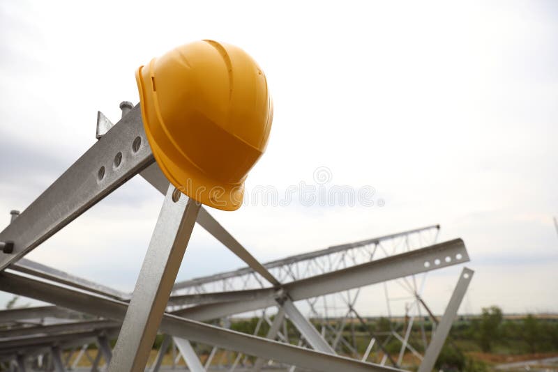 High Voltage Tower Construction with Yellow Hard Hat Outdoors