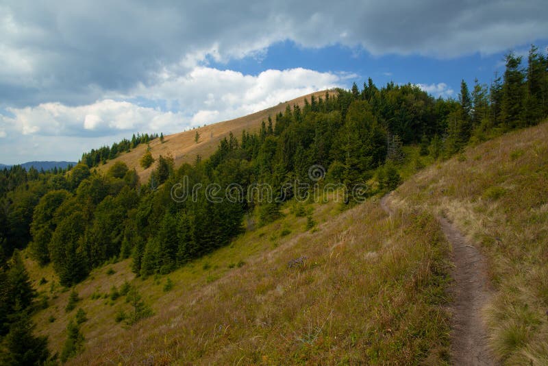 Highland scenic view view mountain and dirt trail for tourists and background landscape of range and forest in cloudy dramatic