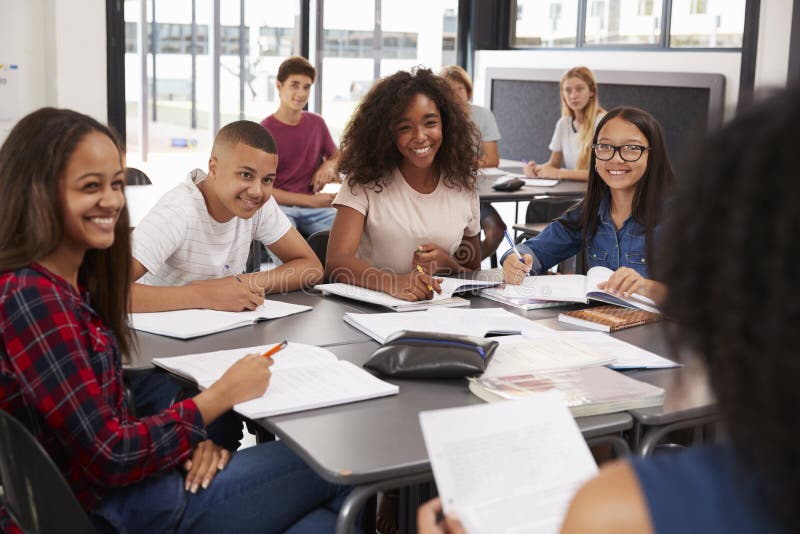 Highschool scherzt das Betrachten zum Lehrer, der ihrem Schreibtisch sitzt