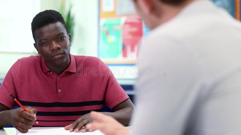 Highschool Tutor Gives Male Student eins bis eins Unterricht am Schreibtisch