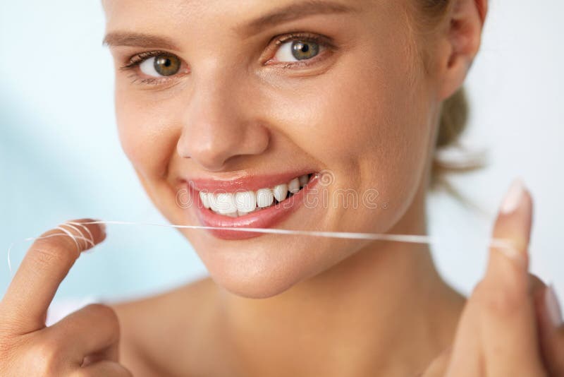 Dental Hygiene. Closeup Of Beautiful Happy Smiling Woman With Beauty Face And Perfect Smile Cleaning, Flossing Healthy White Teeth Using Floss. Oral Health, Tooth Care Concept. High Resolution Image. Dental Hygiene. Closeup Of Beautiful Happy Smiling Woman With Beauty Face And Perfect Smile Cleaning, Flossing Healthy White Teeth Using Floss. Oral Health, Tooth Care Concept. High Resolution Image