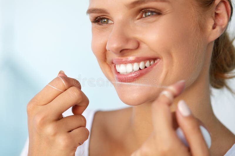 Dental Hygiene. Closeup Of Beautiful Happy Smiling Woman With Beauty Face And Perfect Smile Cleaning, Flossing Healthy White Teeth Using Floss. Oral Health, Tooth Care Concept. High Resolution Image. Dental Hygiene. Closeup Of Beautiful Happy Smiling Woman With Beauty Face And Perfect Smile Cleaning, Flossing Healthy White Teeth Using Floss. Oral Health, Tooth Care Concept. High Resolution Image