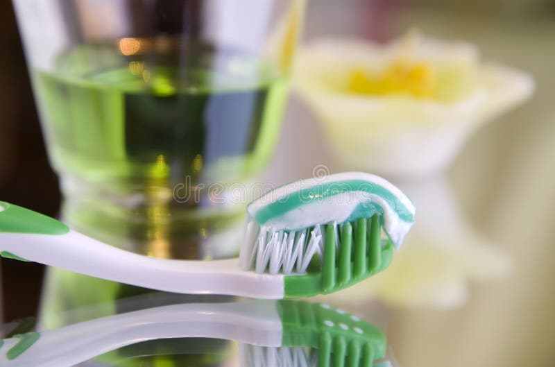 Oral hygiene products - a tooth-brush with toothpaste and rinsing liquid on a mirror surface, close up. Oral hygiene products - a tooth-brush with toothpaste and rinsing liquid on a mirror surface, close up