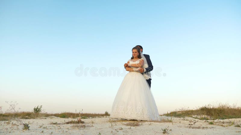 Hij danst in het zomerpark op de achtergrond van de blauwe hemel. bruid en bruidegom op hun huwelijksreis