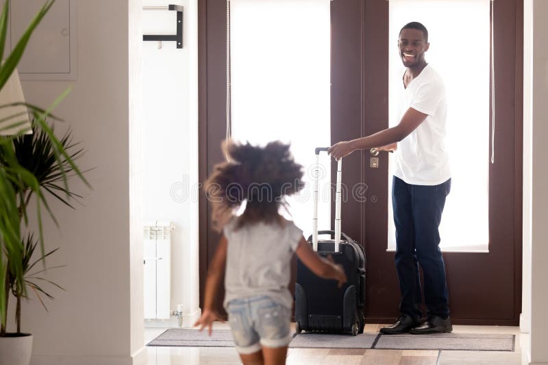 Hija africana que corre para encontrar al padre vuelto de viaje de negocios foto de archivo libre de regalías Hija africana que corre para encontrar al padre vuelto de viaje de negocios foto de archivo libre de regalías