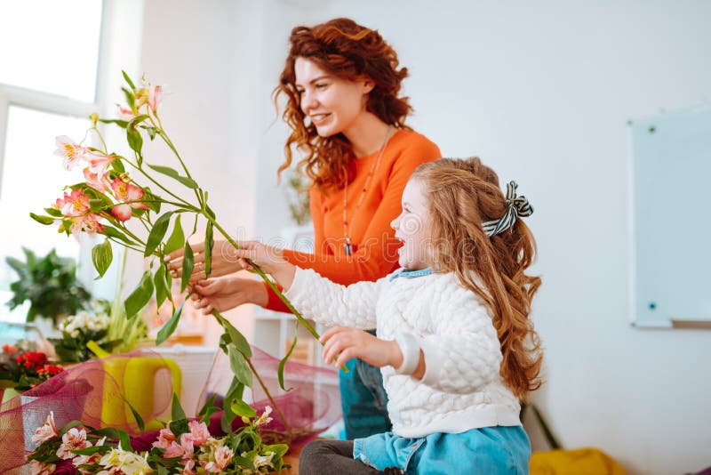 Hija alegre que se divierte mientras que mira las flores con la mamá fotos de archivo libres de regalías Hija alegre que se divierte mientras que mira las flores con la mamá fotos de archivo libres de regalías