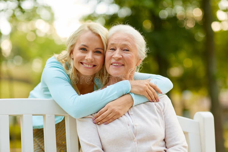 Hija con la madre mayor que abraza en banco de parque fotografía de archivo libre de regalías