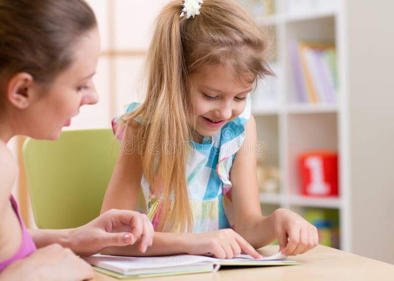 Hija de enseñanza del niño de la madre a leer fotografía de archivo libre de regalías Hija de enseñanza del niño de la madre a leer fotografía de archivo libre de regalías