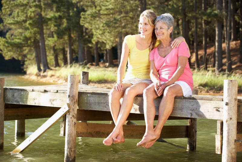 Hija de la madre y del adulto que se sienta por el lago foto de archivo libre de regalías Hija de la madre y del adulto que se sienta por el lago foto de archivo libre de regalías
