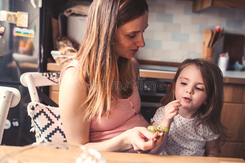 Hija de la madre y del niño que come las uvas para el desayuno en casa imagenes de archivo Hija de la madre y del niño que come las uvas para el desayuno en casa imagenes de archivo