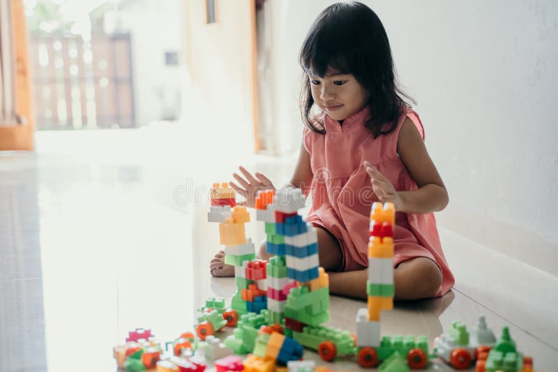 Hija que juega con el ladrillo plástico en casa imágenes de archivo libres de regalías Hija que juega con el ladrillo plástico en casa imágenes de archivo libres de regalías
