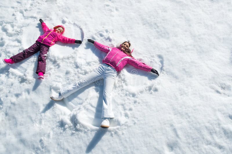 Hija y madre que ponen en nieve fotos de archivo Hija y madre que ponen en nieve fotos de archivo
