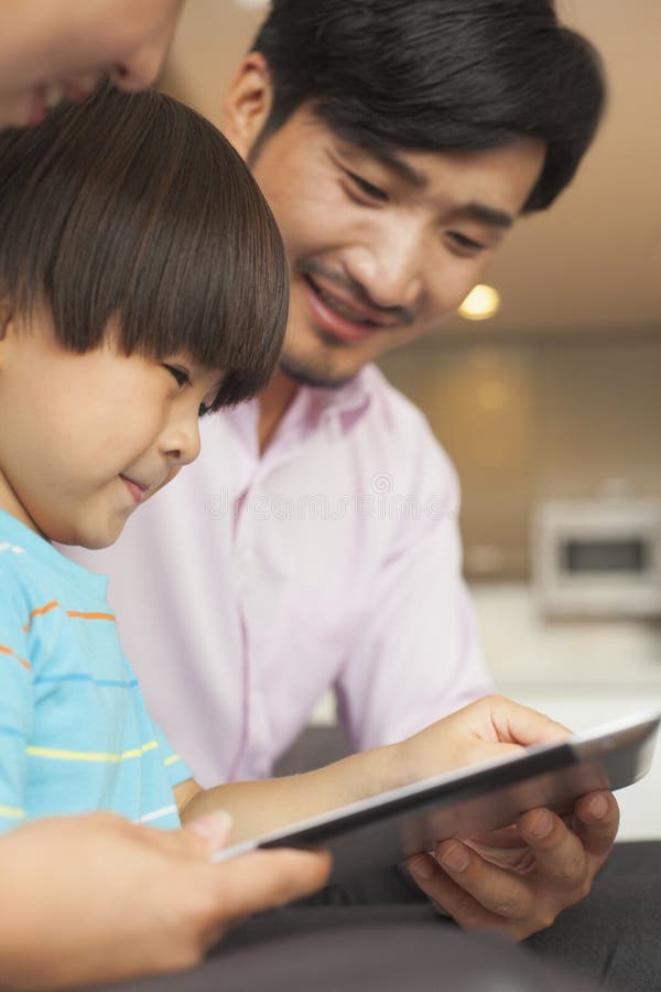 Hijo y sus padres que usan la tableta digital foto de archivo
