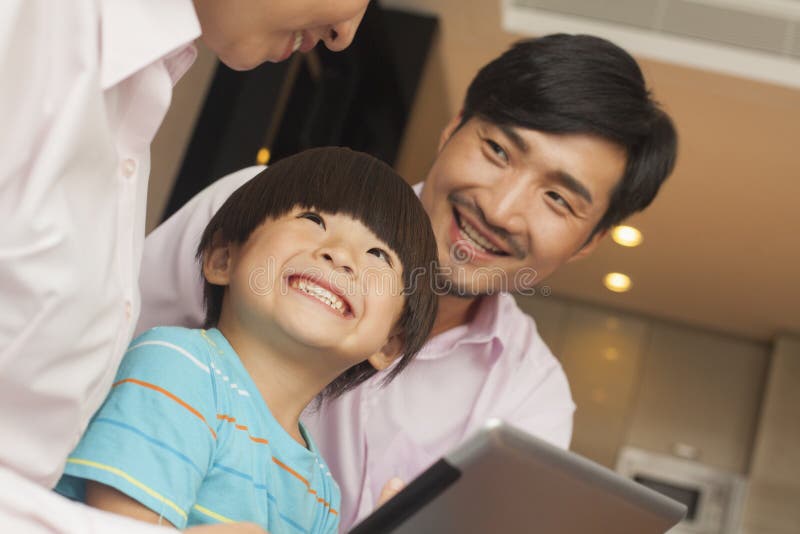 Hijo y sus padres que usan la tableta digital imagenes de archivo