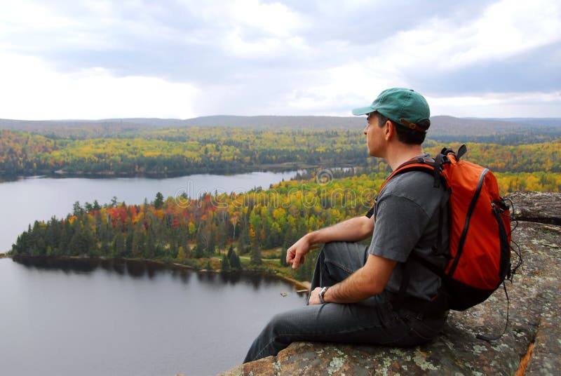 A hiker sitting on a cliff edge enjoying scenic view