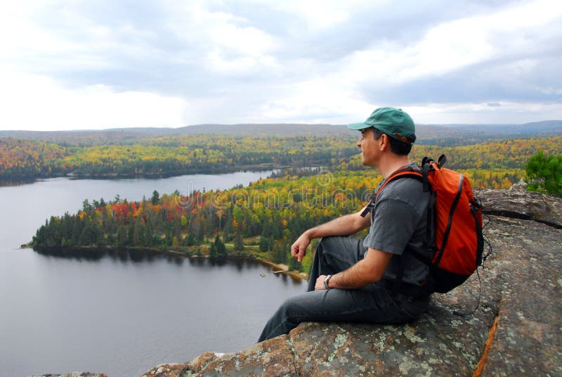 A hiker sitting on a cliff edge enjoying scenic view