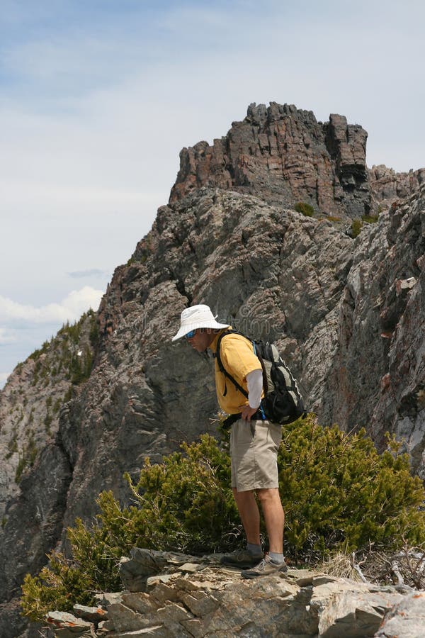 Side view of male hiker looking over edge of rugged mountain. Side view of male hiker looking over edge of rugged mountain.