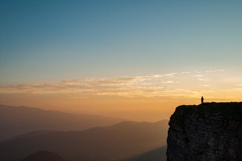 Hiker on the edge of a remote mountain Mangart - a mountain on the border of Slovenia and Italy at sunrise, Europe. Hiker on the edge of a remote mountain Mangart - a mountain on the border of Slovenia and Italy at sunrise, Europe.