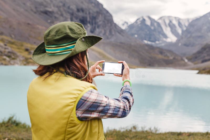 Hiker fotografa un lago di montagna sul suo smartphone fotografia stock Hiker fotografa un lago di montagna sul suo smartphone fotografia stock