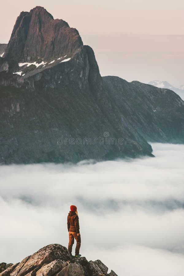 Hiker girl on cliff edge over clouds travel in mountains standing alone adventure extreme journey outdoor Norway active vacations