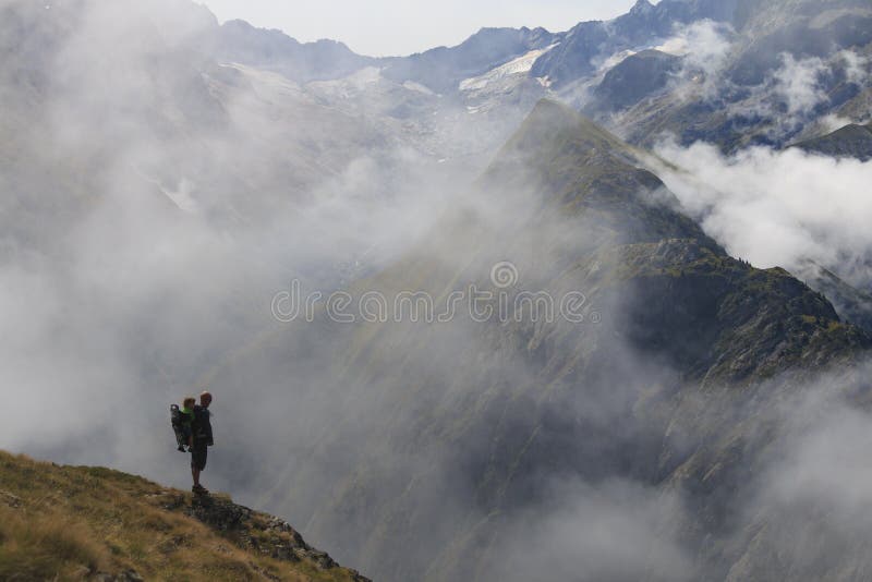 Hiker in France alps standing on edge of mountain with baby on his back. Hiker in France alps standing on edge of mountain with baby on his back.