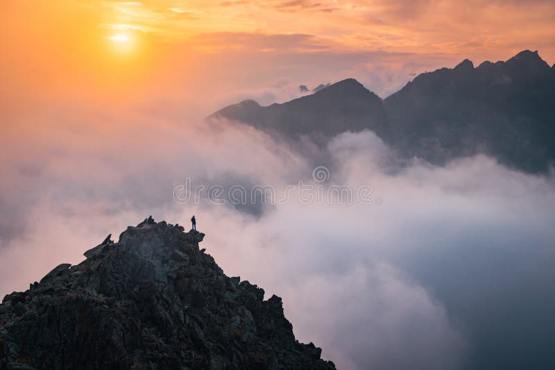 Turista s otevřenou náručí na vrcholu kopce. Krásný západ slunce světlo a mlha v pozadí. Horské scenérie. Upravit prostor