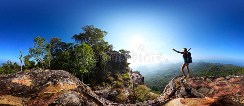 Spherical 360 degrees panorama of a rocky cliff with female hiker standing on an edge with raised hands