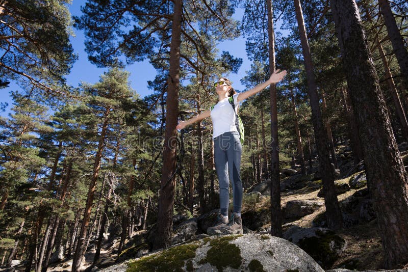 Hiker woman open arms on a great rock in forest