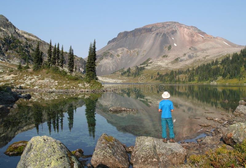 Hiker standing at edge of Ring Lake. Callaghan Valley. British Columbia. Canada.