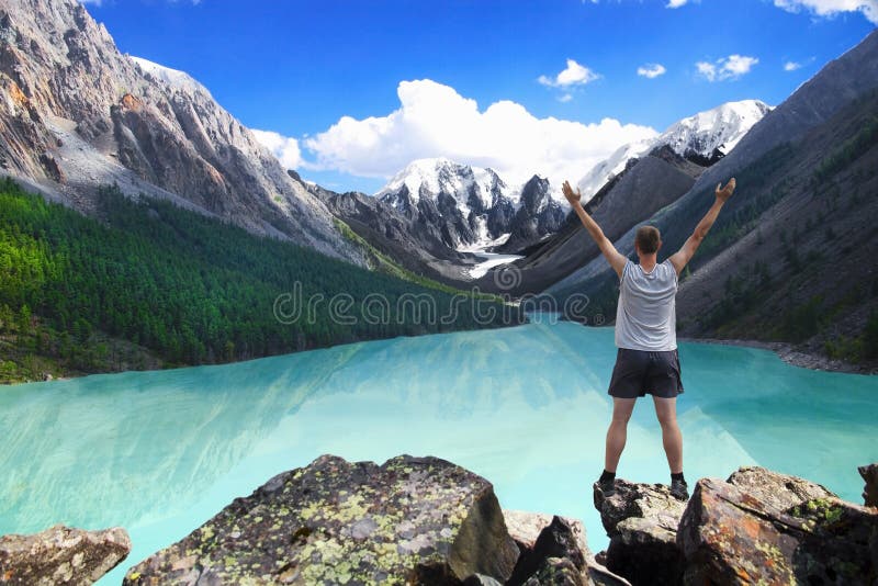 Hiker standing with raised hands near the beautiful mountain lake and enjoying valley view