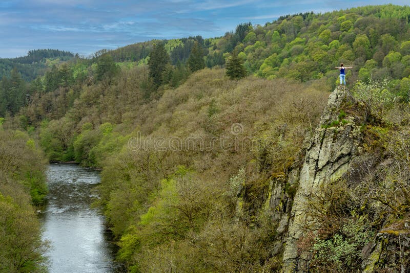 Person standing on the edge of the cliff in natural park Le Herou in belgian Ardennes, admiring beautiful valley with Ourthe river. Person standing on the edge of the cliff in natural park Le Herou in belgian Ardennes, admiring beautiful valley with Ourthe river