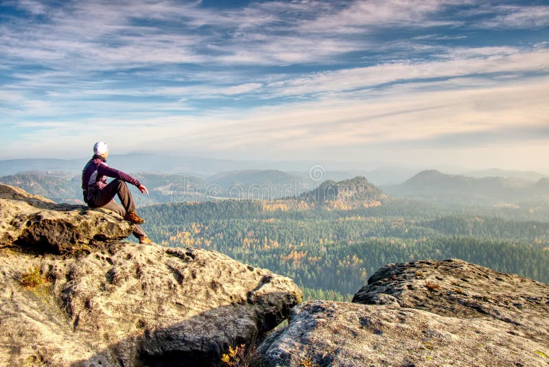 Hiker in trekking clothes sit alone on rock summit. Wonderful daybreak in mountains stock photography Hiker in trekking clothes sit alone on rock summit. Wonderful daybreak in mountains stock photography