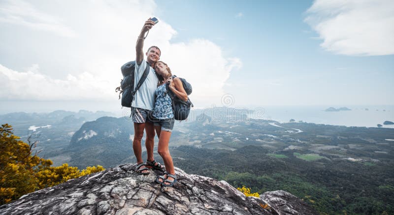 Two hikers taking selfie from top of the mountain with valley view on the background